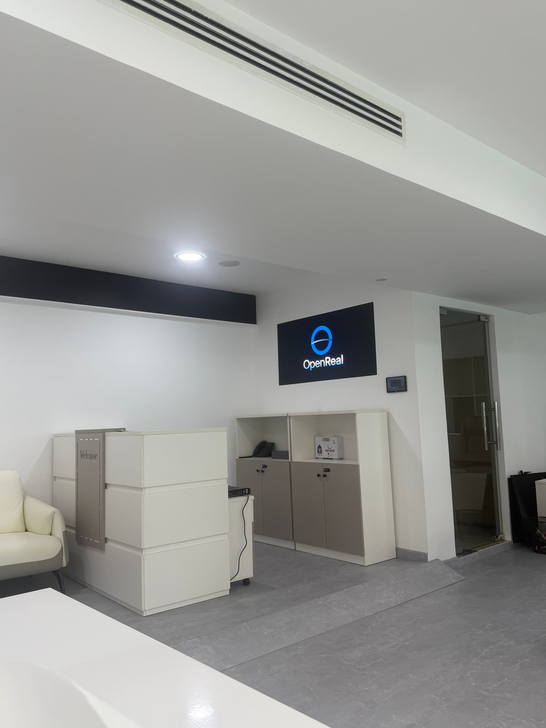 OpenReal reception with the illuminated company logo, welcome desk, and seating.