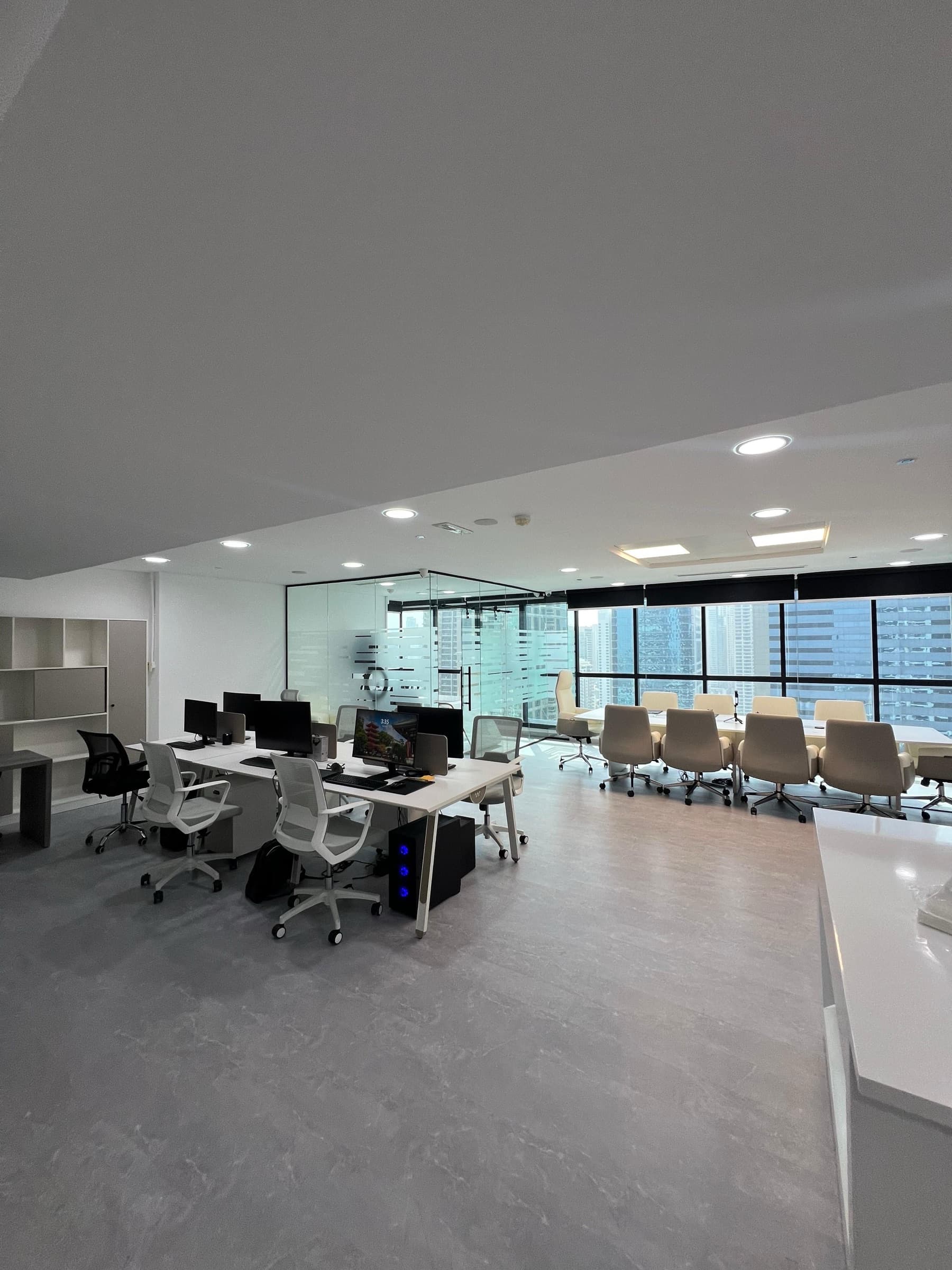 OpenReal workspace with desks, meeting tables, and floor-to-ceiling views of Dubai.